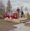 Original title:  [Men and women seated on small stage behind John G. Diefenbaker speaking at podium during northern tour of Canada, Inuvik]. 