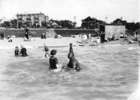 Original title:  Photograph shows Joe Fortes teaching a woman to swim. Other bathers, and West End buildings, can be seen in the background.
Creator: Timms, Philip T. (September 16, 1874 – August 8, 1973)