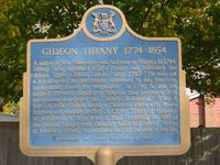 Original title:  Gideon Tiffany 1774-1854 - from OntarioPlaques.com. Photo by Alan L Brown, 2004.

Plaque text: A native of New Hampshire who had come to Niagara in 1794, Tiffany was appointed King's Printer and published the official "Upper Canada Gazette" until 1797. He was not a Loyalist and the government, concerned by his American background, forced his resignation. In 1799 he and his brother Sylvester founded at Niagara this province's first independent newspaper, the "Canada Constellation". When it failed in 1800, Gideon moved to Delaware where, with Moses Brigham and another brother Dr. Oliver Tiffany of Ancaster, he purchased a large tract of land, including the site of the present village, from Ebenezer Allan and others. Active in township affairs, he remained here for the rest of his life. 